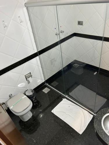 ein Badezimmer mit einem WC und einer Glasduschkabine in der Unterkunft Motel Ibiza in Pará de Minas