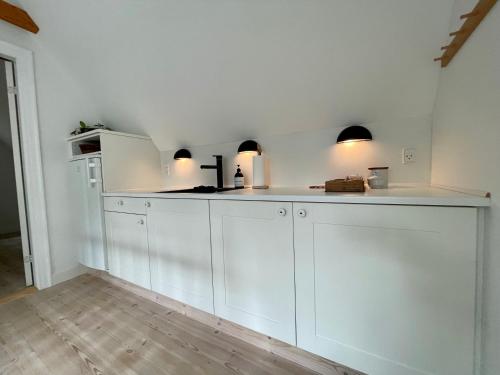 a kitchen with white cabinets and a counter top at Strandby 1847 B&B in Nykøbing Falster