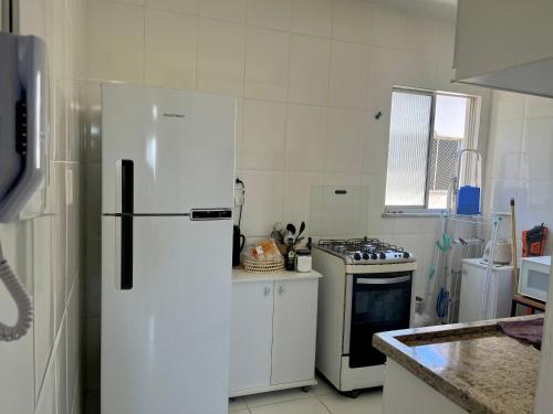 Il comprend une cuisine blanche équipée d'un réfrigérateur et d'une cuisinière. dans l'établissement Apartamento 3/4 ótima localização, à Aracaju