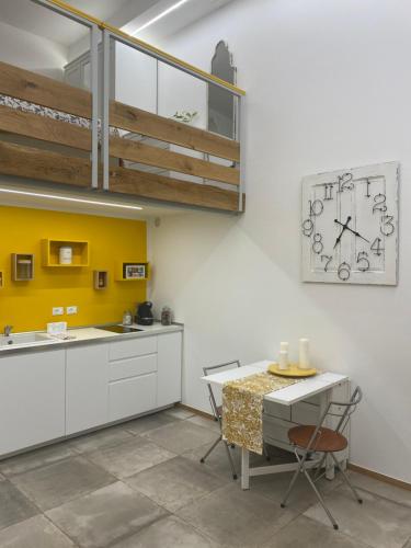 una cucina con armadi bianchi e parete gialla di Silvano Cozy Loft a Bologna