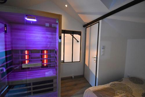 Habitación con una puerta de cristal que conduce a un dormitorio. en Spa de la Nacre, L'étape Repos, en Andeville