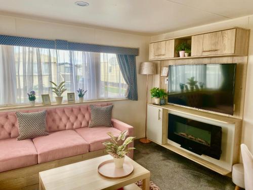 sala de estar con sofá rosa y TV de pantalla plana en The Wardens Retreat - Tattershall Lakes Country Park, en Tattershall