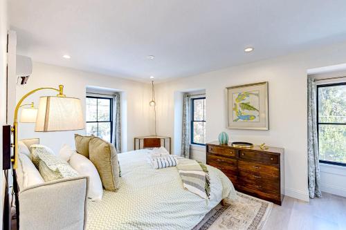 a bedroom with a bed and a dresser and windows at Fun in the Sun in Provincetown