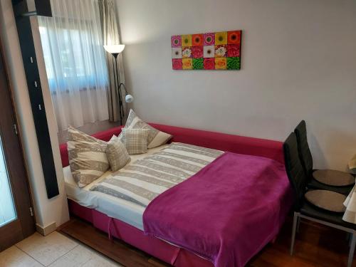 a bed with a purple blanket in a room at Titi Boutique Apartmanok in Bükfürdő