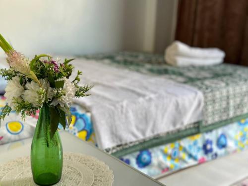 a green vase filled with flowers sitting on a table at Bakar Nubian Guest House in Aswan