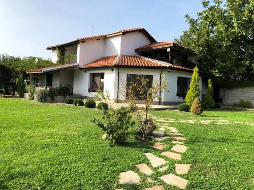 een huis met een groene tuin ervoor bij Къща за гости Сърцето на долината /The Heart of the valley in Enina