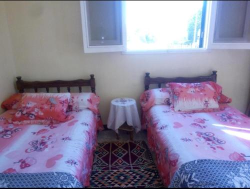 a bedroom with two beds and a table in it at Bakar Nubian Guest House in Aswan