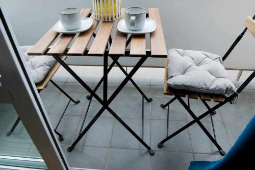 a wooden table with two cups and two chairs at Céntrico apartamento y parking a 200m de la playa in Palamós