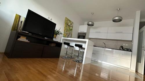 a living room with a television and a counter with stools at Studio apartman Luce self CHECK IN in Osijek