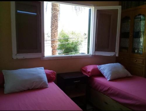 two beds sitting in a room with a window at Bakar Nubian Guest House in Aswan