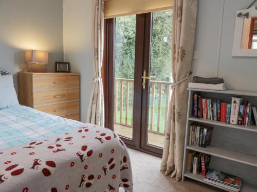 a bedroom with a bed and a book shelf with books at Roe Deer Lodge in Newton Stewart
