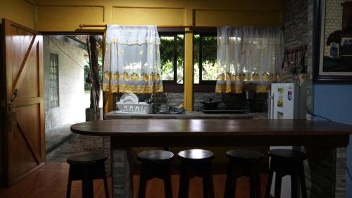 a kitchen with a wooden table and stools at MIRAVALLES RANCHO - Rio Celeste Dreams in Bijagua