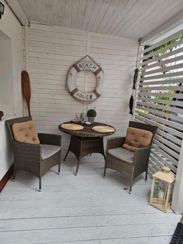 een patio met een tafel en stoelen en een bord bij Beach House in Międzyzdroje