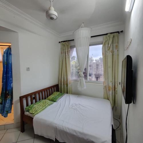 a bedroom with a bed and a tv and a window at The Majestic Royal Palms, Mtwapa in Shimo la Tewa
