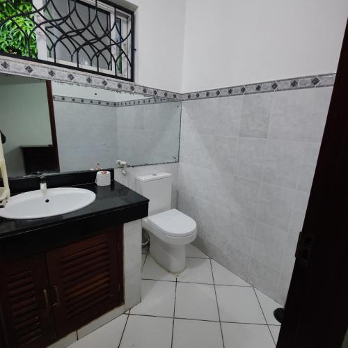 a bathroom with a toilet and a sink and a mirror at The Majestic Royal Palms, Mtwapa in Shimo la Tewa
