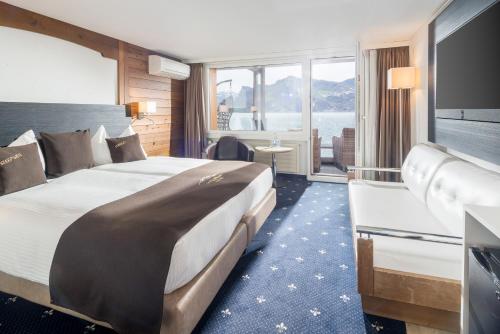 a hotel room with a large bed and a large window at Seehotel Pilatus in Hergiswil