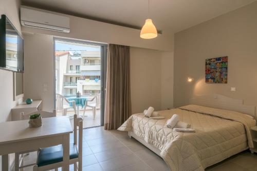 a bedroom with a bed and a table and a balcony at Aloe Apartments in Rethymno
