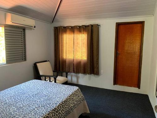 - une chambre avec un lit, une chaise et une fenêtre dans l'établissement Chácara com 2 piscinas e 3 suítes, à Campo Grande