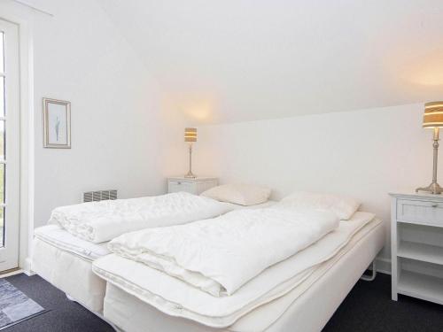 a white bedroom with two white beds and a window at Holiday Home Troldbjergvej IV in Gjern