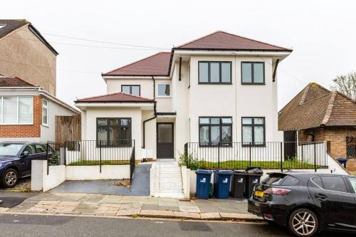 a white house with a car parked in front of it at Massive west London 7 bed modern in London