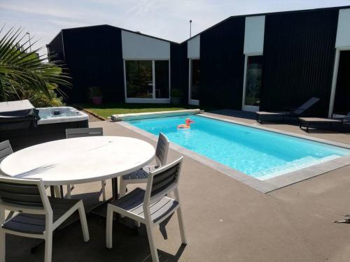 聖屈艾波爾特里厄的住宿－Maison avc Piscine, Spa Etables Mer proche plages，一个带桌椅和桌子的游泳池以及一个游泳池