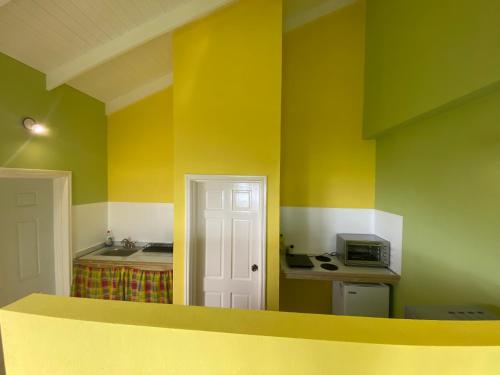 a kitchen with yellow and green walls and a microwave at Greenhouse on the Hill, Sea View Studio Apartment in Laborie