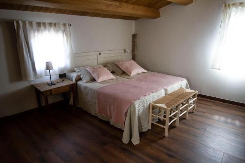 a bedroom with a bed with pink pillows and a table at La Creu de la Pinya in Berga