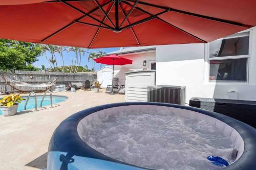 a hot tub under an umbrella on a patio at Beach House/KING BD/Hot Tub/Pool/Fire Pit/Gym/Golf in Lantana