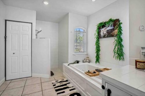 a white bathroom with a tub and a window at Beach House/KING BD/Hot Tub/Pool/Fire Pit/Gym/Golf in Lantana