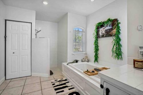 a white bathroom with a tub and a window at Beach House/KING BD/Hot Tub/Pool/Fire Pit/Gym/Golf in Lantana