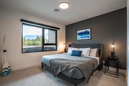 a bedroom with a bed and a large window at Revy's Peak Condo - Hot Tub with View in Revelstoke