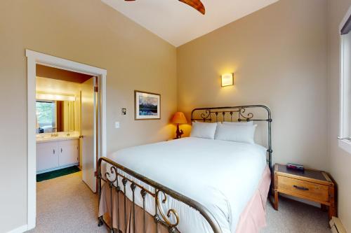 a bedroom with a large white bed and a bathroom at Moose Creek Lodge in Wilson