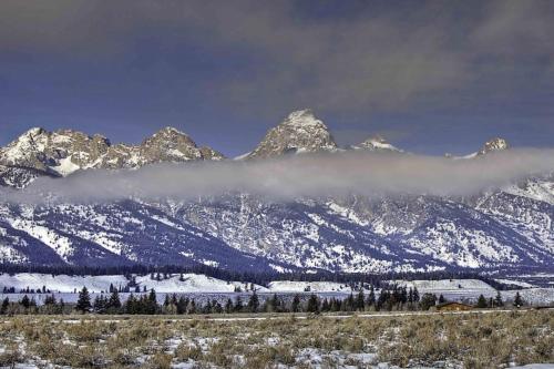 a snow covered mountain range with a fog in the foreground at Moose Creek Lodge in Wilson