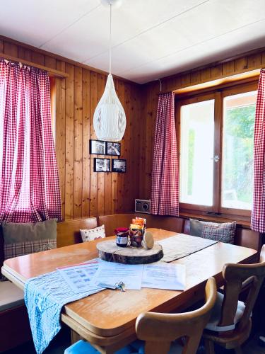 comedor con mesa de madera y cortinas rojas en Felsenberg - CharmingStay, en Flumserberg