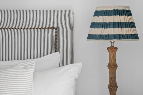 a lamp sitting next to a bed with white pillows at Little Sandy House, Rhosneigr in Rhosneigr