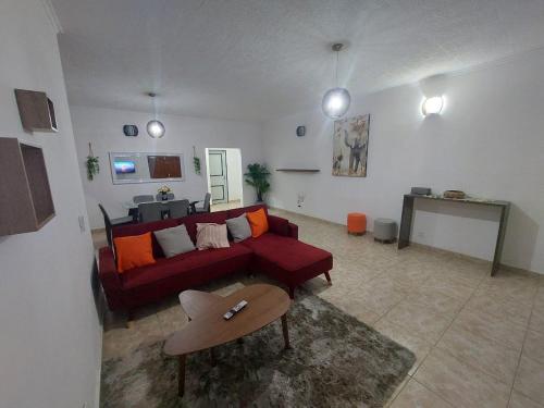 un soggiorno con divano rosso e tavolo di Appartements Haut de Guégué a Libreville