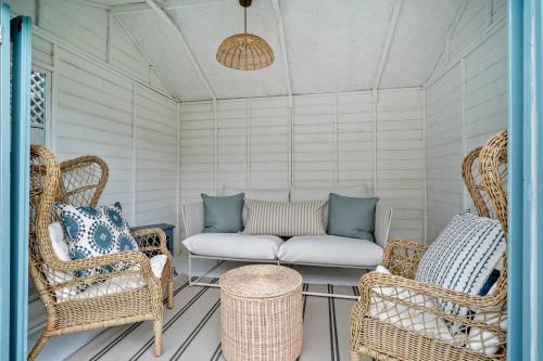 a porch with wicker chairs and a couch at Little Sandy House, Rhosneigr in Rhosneigr
