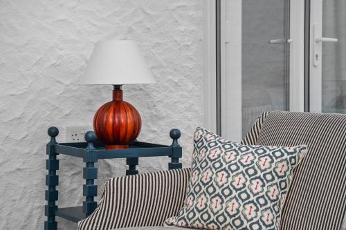 a lamp on a table next to a chair with a pillow at Little Sandy House, Rhosneigr in Rhosneigr