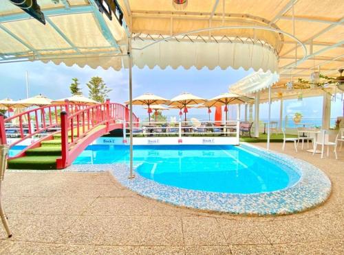 una gran piscina con un puente y una sombrilla en Plaza Corniche en La Marsa