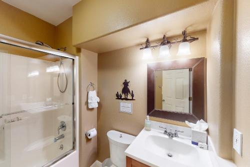 W łazience znajduje się umywalka, toaleta i lustro. w obiekcie Ski Retreat w Almie