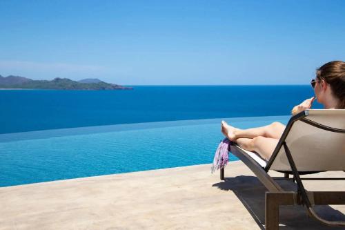 a woman sitting in a chair by the water at 360 Splendor - Ocean-View Condo #204 in Luxury Flamingo-Complex in Playa Flamingo