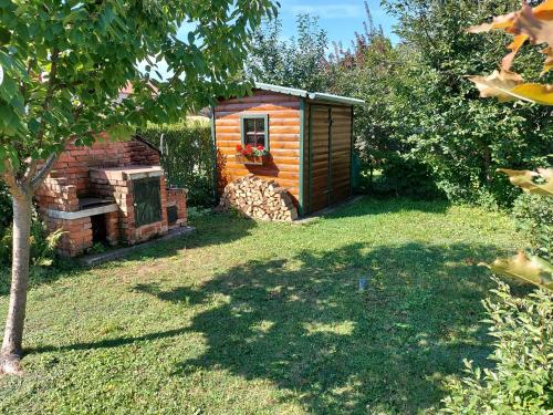 a small wooden cabin in a yard with a tree at Titi Boutique Apartmanok in Bükfürdő