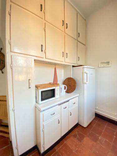 La cuisine est équipée de placards blancs, d'un four micro-ondes et d'un réfrigérateur. dans l'établissement Charmant haut de villa T3, à Saint-Cyr-sur-Mer