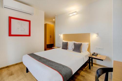 um quarto de hotel com uma grande cama branca e uma mesa em Hotel Q Rooms BTM Layout Near Gopalan Innovation Mall em Bangalore
