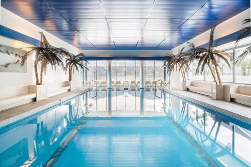 a swimming pool with palm trees in a building at Seehotel Pilatus in Hergiswil