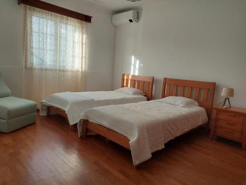 a bedroom with two beds and a chair and a window at Casa da Adega in Ribeira Chã