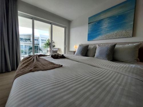 a large bed in a bedroom with a large window at Beach Haven 1BDR Condo Paseo Playa Coral - 305 in Punta Cana