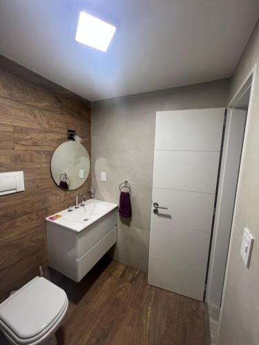 a bathroom with a toilet and a sink and a mirror at Rivadavia Deluxe in Mariano J. Haedo