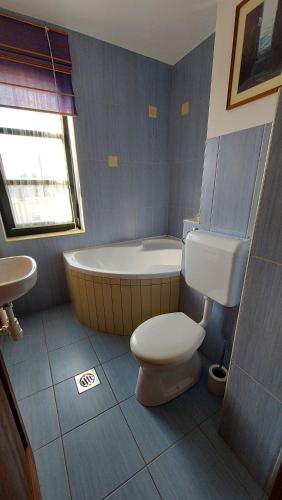 a bathroom with a tub and a toilet and a sink at Titi Boutique Apartmanok in Bükfürdő