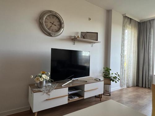 a living room with a tv and a clock on the wall at Apartment Stella in Varna City